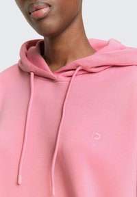 Roze hoodie met een zachte textuur, voorzien van een kangoeroezak, verstelbare capuchon met trekkoord en een subtiel logo op de borst.