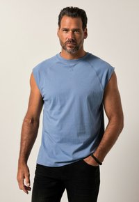 Jasnoniebieska, bezrękawnikowa koszulka z okrągłym dekoltem, wykonana z miękkiego materiału, o luźnym kroju. Prosty design z minimalną ilością szwów.