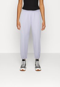 Světle fialové tepláky s elastickým pasem a manžetami na kotnících. Obsahují decentní detaily prošívání a logo na boku.