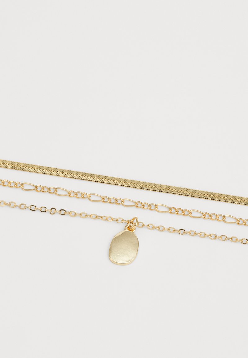 Goldfarbene, geschichtete Halskette mit drei Ketten: einer Schlangenkette, einer langen Gliederkette und einer Kette mit einem ovalen Anhänger.