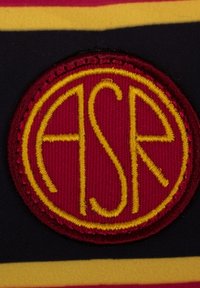 Rode ronde patch met geborduurde gele letters "ASR" op een gestructureerde marineblauwe achtergrond, versierd met horizontale strepen in rood en geel.