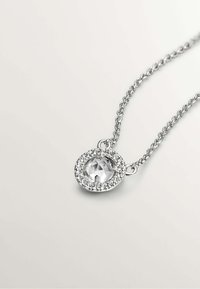 Collar de plata con un colgante de cristal transparente en forma de círculo, rodeado de piedras transparentes más pequeñas, con un diseño de cadena delicado.