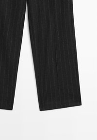 Černé pruhované kalhoty se rovnými nohavicemi, s jemnou texturou a čistým zakončením na lemech. Bez viditelného kovového doplňku nebo akcentů.
