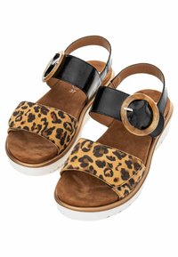 Sandal met luipaardprint, een bruine suède band, glanzende zwarte banden en een oversized ronde gesp; witte zool met een gestructureerde rand.