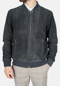 Wildleder-Bomberjacke in Dunkelgrau mit gerippten Bündchen und Saum. Verfügt über einen vorderen Reißverschluss und zwei seitliche Reißverschlusstaschen. Glatte Textur.