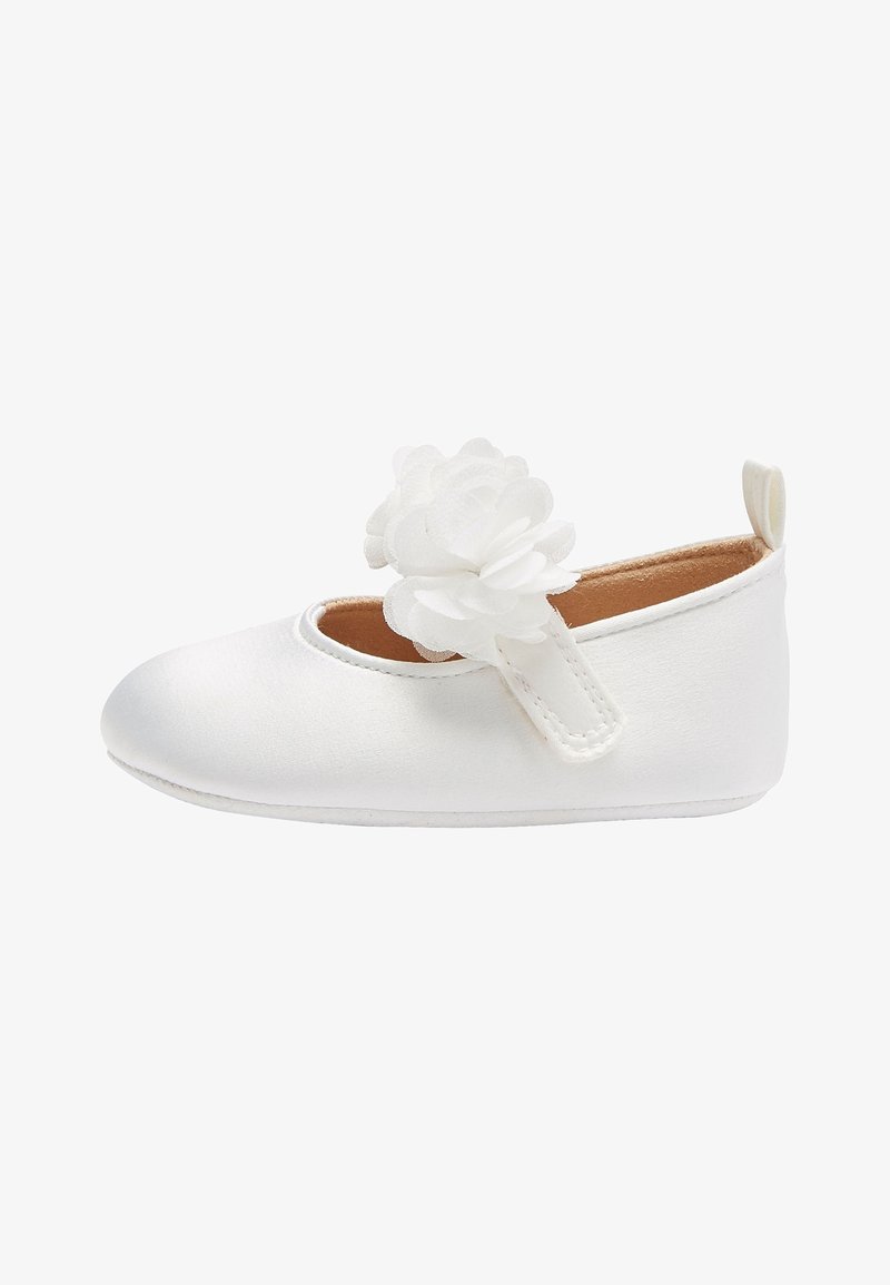 Zapato de bebé blanco con una flor de tela en la correa, suela blanda y una lengüeta en el talón, diseñado para bebés.