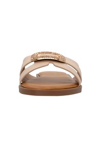 Infradito beige con design a strap incrociati, dotati di un accento di gioiello. Suola liscia con una texture simile al legno naturale.