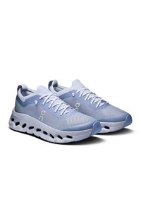 Baskets de sport bleu clair avec une tige en mesh respirant, des accents texturés et une semelle rembourrée présentant des découpes circulaires et une pointe arrondie.