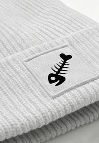 Gray ribbed knit beanie featuring a square patch with a black fishbone graphic. The fabric appears soft and textured.