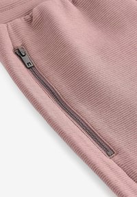 Rosenribbet stof med en sidelukket lomme. Den slanke lynlås hardware tilføjer en funktionel detalje til det teksturerede materiale og design.