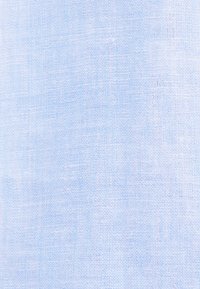 Gros plan sur un tissu tissé bleu clair montrant une texture fine et des fils qui se croisent.