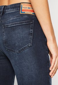 Tumma siniset farkut, kapeat lahkeet ja korkea vyötärö, joissa on yksi takatasku ja merkkikohtainen nahka-etiketti takana.