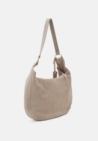 Hobo-Tasche aus beigem Wildleder, mit einer geschwungenen Form, einem einzelnen verstellbaren Tragegurt und dezent genähten Paneelen für zusätzliche Textur und Details.