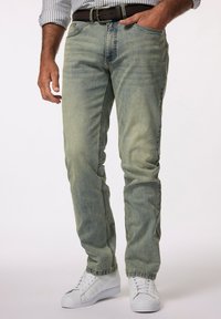 Jeans de mezclilla de lavado claro con un corte recto, que presentan un sutil desgaste y detalles de costura, combinados con zapatillas blancas.