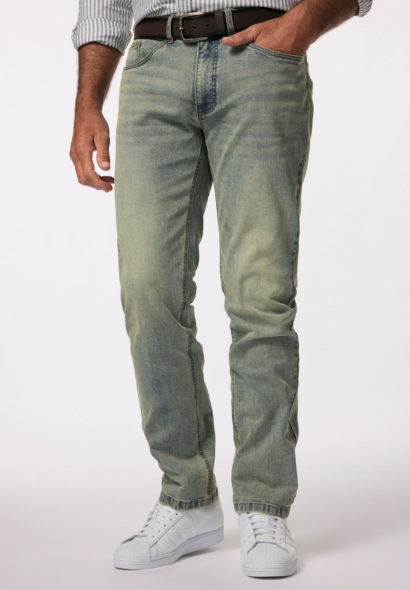 Jeans de mezclilla de lavado claro con un corte recto, que presentan un sutil desgaste y detalles de costura, combinados con zapatillas blancas.