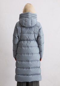 Lange, lichtblauwe pufferjas met horizontale naden en een capuchon, met een gladde, glanzende textuur en een iets getailleerde pasvorm.