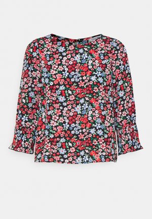 Blomstret bluse med sort baggrund, der har en blanding af røde, pink og blå blomster. Lange ærmer med flæseender og rund halsudskæring.