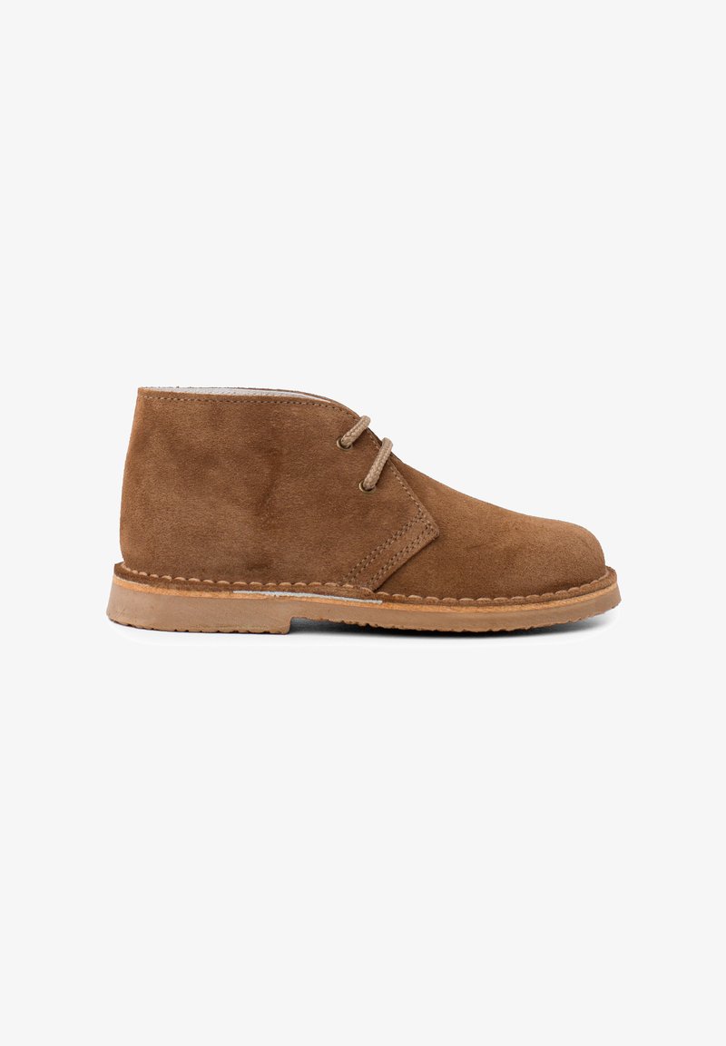 Stivale ankle in suede beige con punta arrotondata, due occhielli per i lacci e suola in gomma marrone chiaro. Dettagli di cucitura attorno alla base.