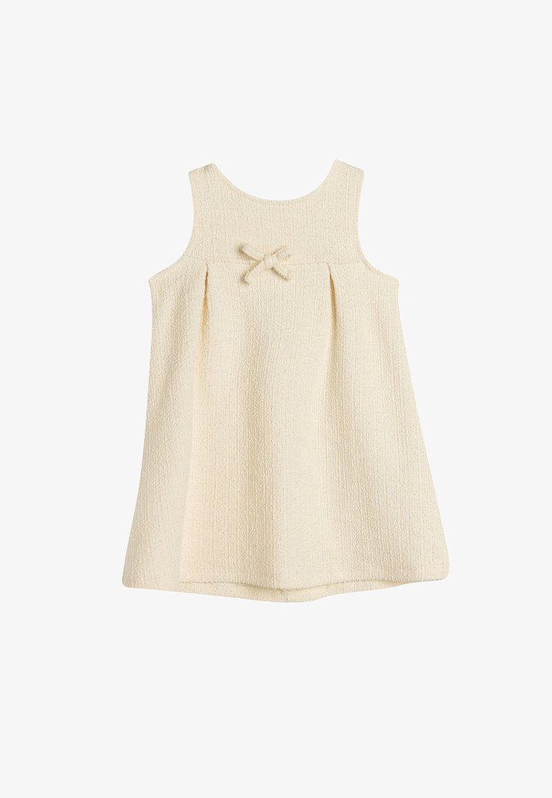 Helles cremefarbenes ärmelloses Kleid aus strukturiertem Stoff, mit rundem Ausschnitt und einem kleinen Schleifchen vorne.