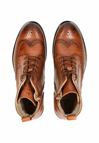 Stivali alla caviglia in pelle marrone con lacci, accentuati da forature, dettagli brogue, punte arrotondate, cuciture visibili e suole nere texture.