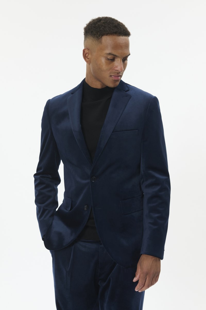 Tumši zils zamša žakete ar vienu pogu, ar izgriezuma atloku un krūšu kabatu, kombinēts ar melnu augstu apkakli. Pielāgota piegriezuma.