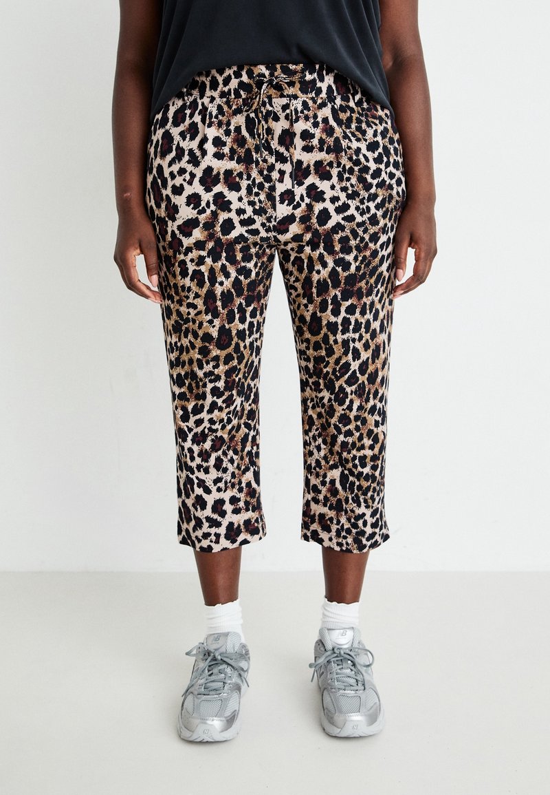Beige, leopardprint cropped broeken met een trekkoord in de taille en een gladde textuur. Draagt met grijze sneakers en witte sokken.