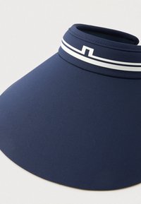 Sinalna mornarsko modra tkanina sončna kapa s široko obrobo in belimi geometrijskimi črtami v bližini zgornjega roba.