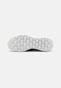 Weißer Sneaker-Sohle mit strukturiertem Muster, ausgestattet mit Rillen für Traktion und einer leichten Kurve, aus flexiblem Gummi für Komfort.
