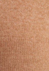 Tissu tricoté brun clair avec une texture douce. Présente un motif côtelé, créant une apparence confortable et chaleureuse.