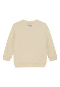 Beiger Sweatshirt mit langen Ärmeln und gerippten Bündchen sowie Saum, auf dem oberen Rücken ist ein kleines weißes Etikett mit rotem und schwarzem Text zu sehen.