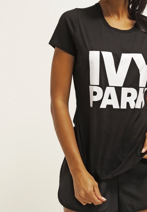 Camiseta negra de manga corta con el gran texto blanco "IVY PARK" en la parte frontal. Tela suave, escote redondo, corte casual.