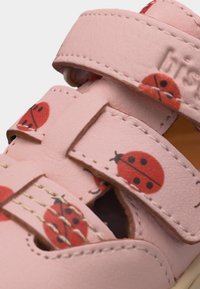 Ροζ παιδικό σανδάλι με ρυθμιζόμενα λουριά, διακοσμημένο με κόκκινες πασχαλίτσες και εμφανείς ραφές.