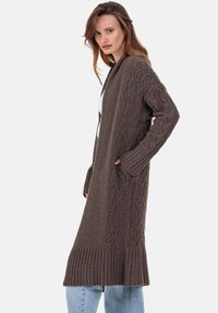 Cardigan long marron avec motifs torsadés sur les manches et le devant, ourlet côtelé, ouverture frontale et poches latérales.