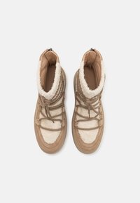 Bottes tan et beige avec doublure en fourrure, matériau texturé sur les orteils et la partie supérieure, maintenues par des lacets marron et une fermeture éclair à l'arrière.