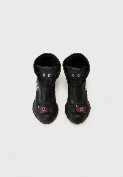 Juodi slip-on batai su tekstūruotu paviršiumi, turintys platų dirželį su logo ir raudonais akcentais. Sukurti patogiam dėvėjimui.