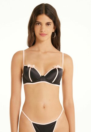 Schwarzer Satin-BH mit rosa Akzenten, ausgestattet mit Bügeln, verstellbaren Trägern und kleinen Schleifen auf jeder Tasse. Einfaches und strukturiertes Design.