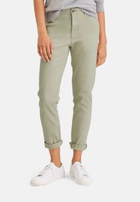 Ljusgröna bomullschinos med uppvikta ärmar, med platt front och sidofickor, som är parat med vita sneakers.