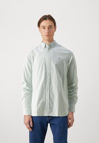 Camicia button-up verde chiaro con un motivo sottile, maniche lunghe e colletto classico. Presenta un piccolo logo sul petto.