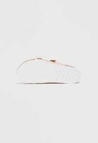 Ροζ παπούτσια με λευκή ελαστική σόλα σε κυματιστό σχέδιο. Έχουν απαλό άνω μέρος, καφέ λεπτομέρειες και απλό, στρογγυλό σχέδιο.