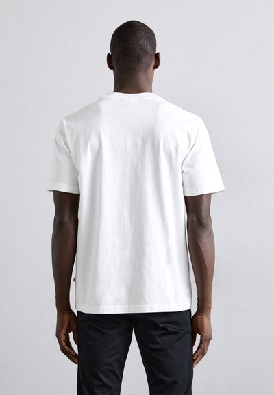 Camisa de algodón blanca con cuello redondo y mangas cortas, que presenta un diseño limpio y un acabado ligeramente texturizado en la tela.