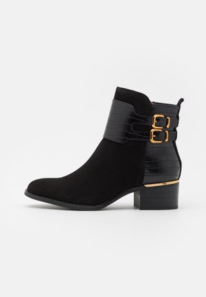 Czarne botki sięgające kostki, wykonane z zamszu i sztucznej skóry krokodyla, z dwoma złotymi klamrami oraz kontrastującą teksturowaną wstawką, na słupkowym obcasie.