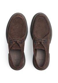 Chaussures en daim marron avec un bout rond, semelles intérieures en cuir, deux œillets pour les lacets et un fil de contraste le long des bords. Semelles en caoutchouc.