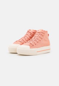 Höga sneakers i persikofärgad stickad tyg med gummitå och texturerad sula. Har matchande snören och en subtil vit rand på sulan.