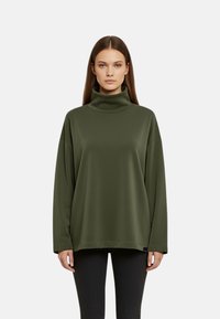 Maglione a collo alto oversize verde oliva in tessuto liscio, con spalle scese e vestibilità rilassata. Cucitura orizzontale all'orlo.