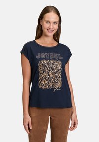 Navy blue T-shirt with short sleeves, featuring a textured gold print saying "JOYFUL" and a patterned graphic in the center.