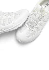 Scarpe sportive bianche realizzate con un mix di pelle liscia e materiali in rete, con punta arrotondata e un sistema di allacciatura centrale. Dettagli di texture sottili.