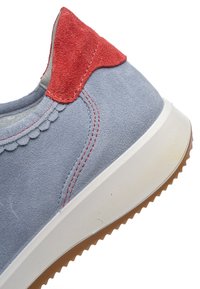 Scarpa in pelle scamosciata blu con dettaglio in pelle scamosciata rossa sul tallone, caratterizzata da un motivo smerlato e una suola in gomma bianca con una suola esterna marrone strutturata.