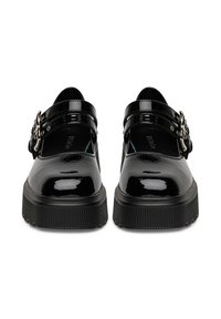 Zapatos de charol negro con dos correas ajustables con hebilla, suela gruesa y texturizada, punta redonda y acabado brillante.