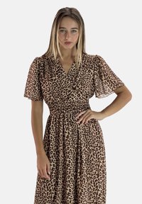 Robe à imprimé léopard avec des manches courtes à bouffant, une taille smockée et une jupe fluide. Le tissu présente un matériau texturé et léger.