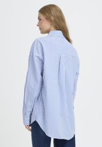 Blue and white striped button-up shirt featuring a relaxed fit, long sleeves, a back yoke, and rounded hem. Made from lightweight fabric.